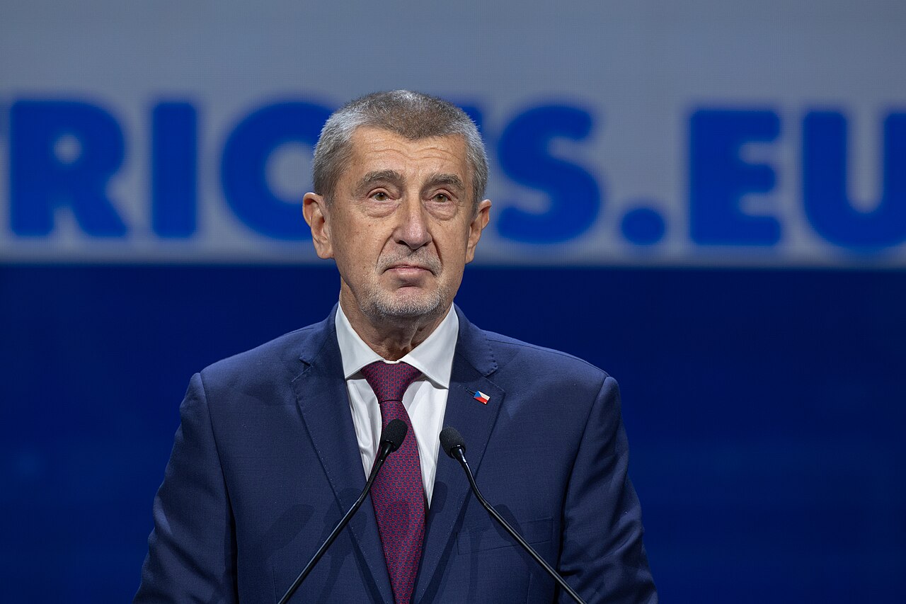 Andrej Babiš in a navy suit standing behind two microphones at the Madrid summit in February 2025.
