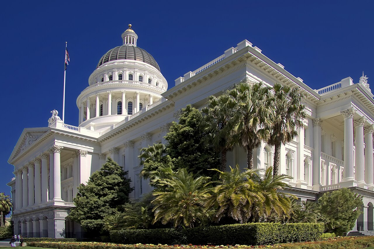 California State Capitol in Sacramento with lawn, trees and palms in front